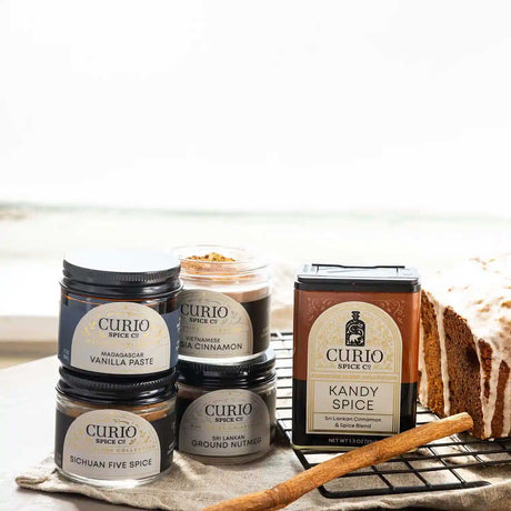 Curio Spice Co. spice jars on a kitchen counter with a loaf of bread in the background.