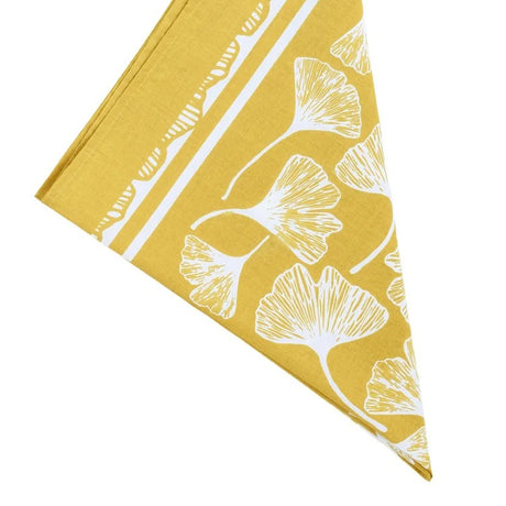 Yellow bandana folded in a triable with white ginkgo leaf pattern on a white background