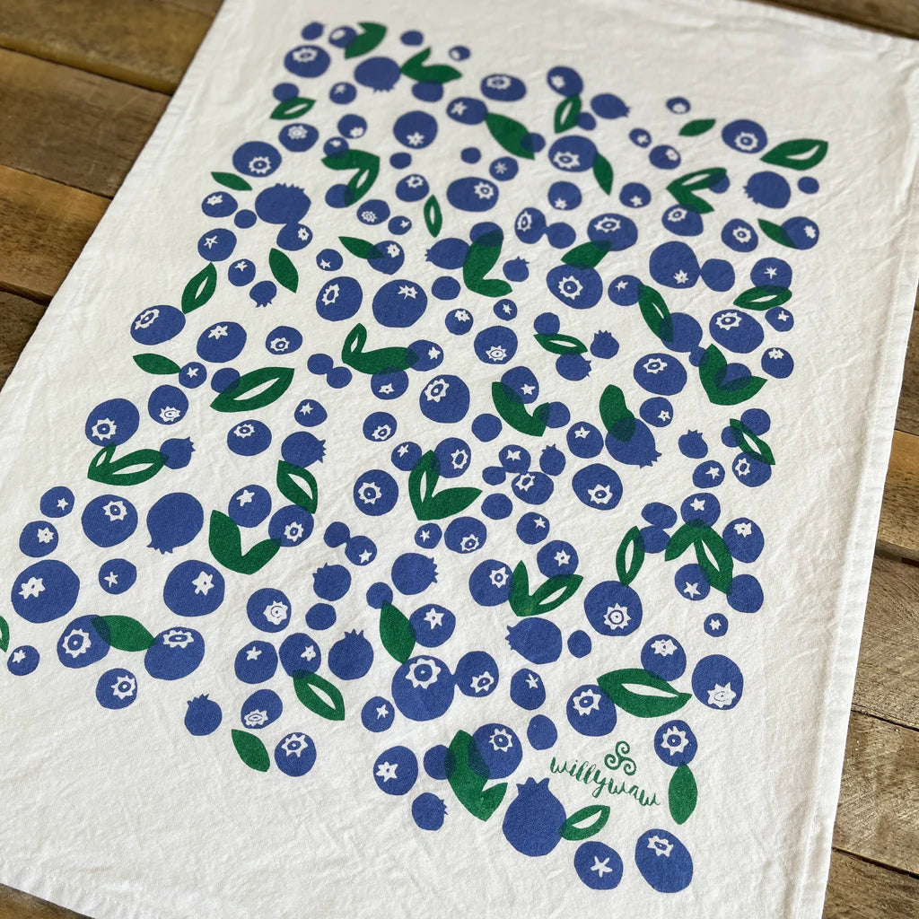White towel with blueberry pattern and 'willywaw' branding on a wooden surface