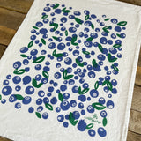 White towel with blueberry pattern and 'willywaw' branding on a wooden surface