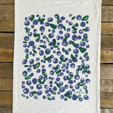 White towel with blueberry pattern on a wooden surface