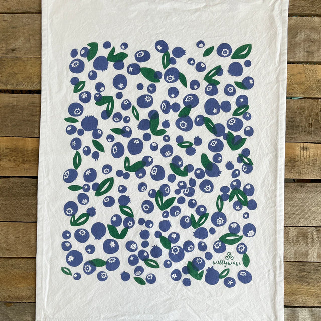 White towel with blueberry pattern on a wooden surface