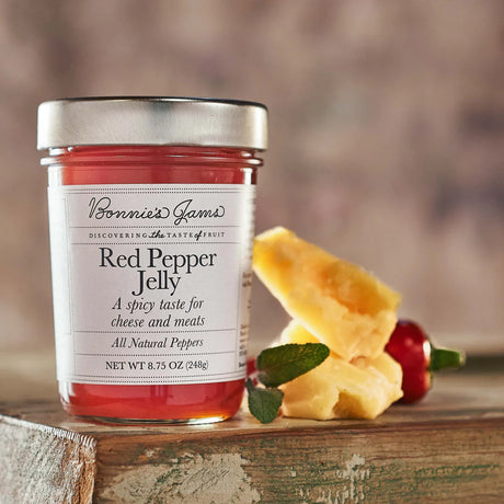 Jar of Red Pepper Jelly with cheese and pepper on a wooden surface