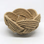 a hand woven cotton rope bowl in tan against a white background