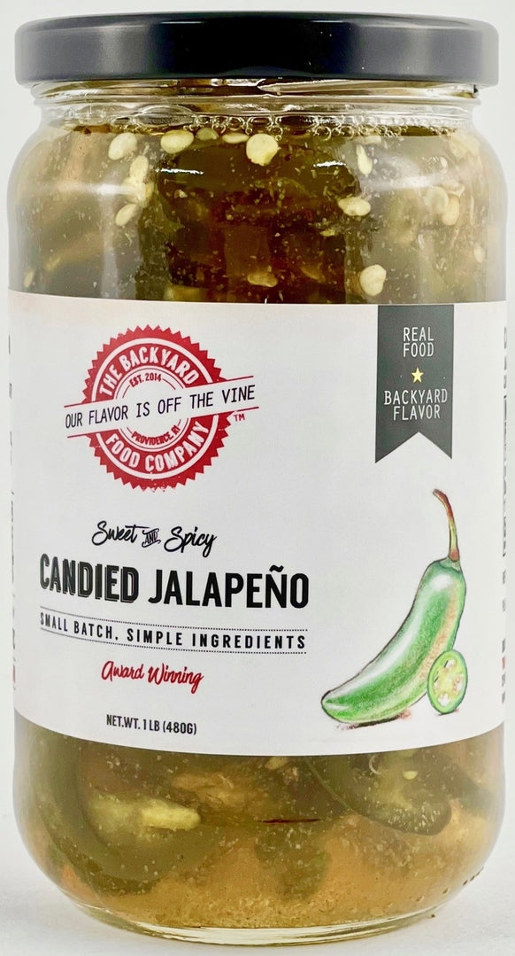 A jar of Backyard Candied Jalapeño from Backyard Food Company, featuring a white label with red and black text, a black lid, and visible sliced jalapeños and garlic in the brine.