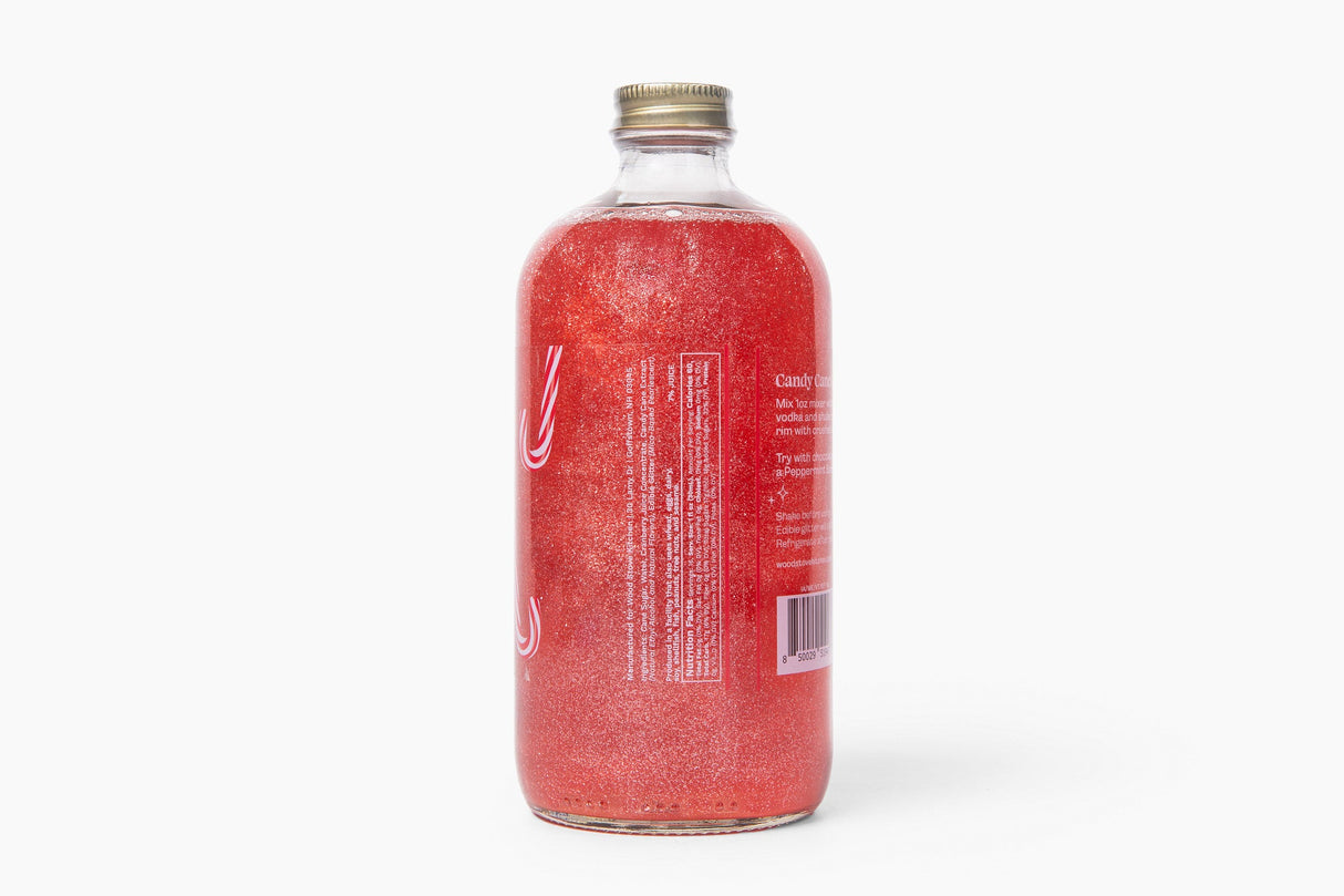A clear glass bottle filled with sparkling pinkish-red liquid, shown from the back against a clean white background. The bottle has a gold screw cap and a white label with text, though the text is not fully legible.