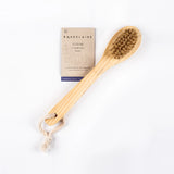 Wooden facial brush with bristles and packaging on a white background