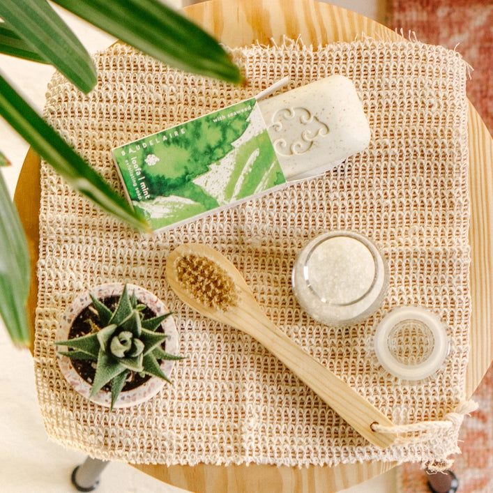 Natural skincare products on a textured surface with a plant in the background