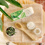 Natural skincare products on a textured surface with a plant in the background
