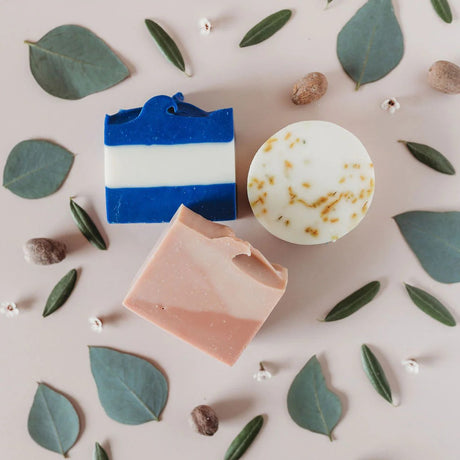 the three soaps in the Day at the Beach soap set surrounded by leaves and elements of the soap fragrances
