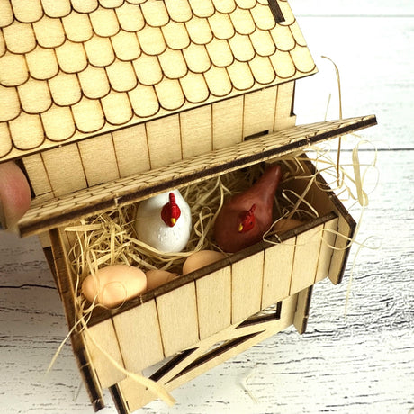 Miniature wooden chicken coop with chickens and eggs on a wooden surface