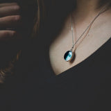 Necklace with a moon pendant worn by a person against a dark background
