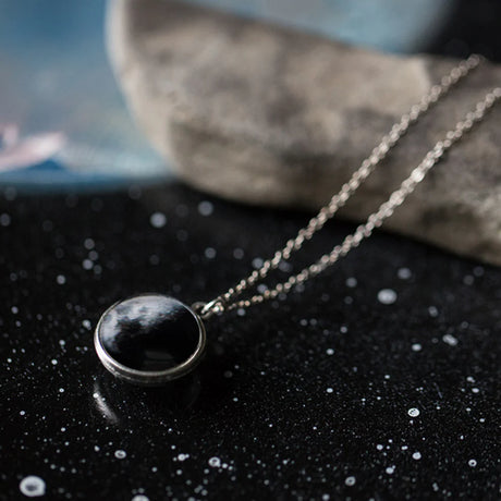 Necklace with a moon pendant on a dark surface