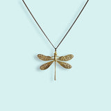 Gold dragonfly pendant necklace on a light blue background