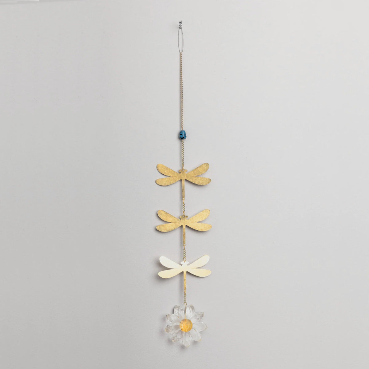 Decorative hanging with gold dragonflies and a white flower on a gray background