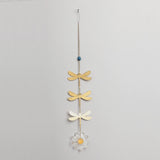 Decorative hanging with gold dragonflies and a white flower on a gray background