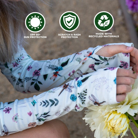 a close up of a model wearing the dragonfly meadow protection sleeves in the garden, showing off the convenient thumb hole. text on the image reads "UPF 50+ Sun protection, Scratch & Rash protection, and made with recycled materials"