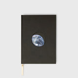 Black notebook with a circular cutout showing Earth on a white background