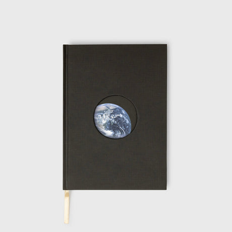 Black notebook with a circular cutout showing Earth on a white background