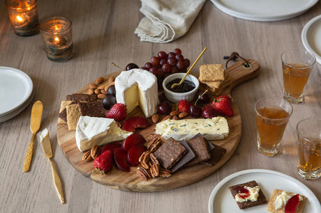 a snack spread of Effie's biscuits with cheese and fruit on a wood table surrounded by drinks and utensils