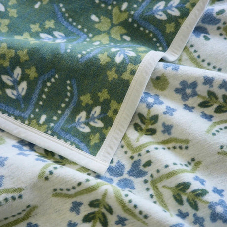 Close-up of patterned blanket with green, blue, and white floral design.