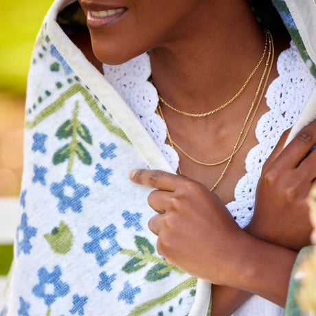 Woman wrapping herself in a floral-patterned blanket with a blurred background