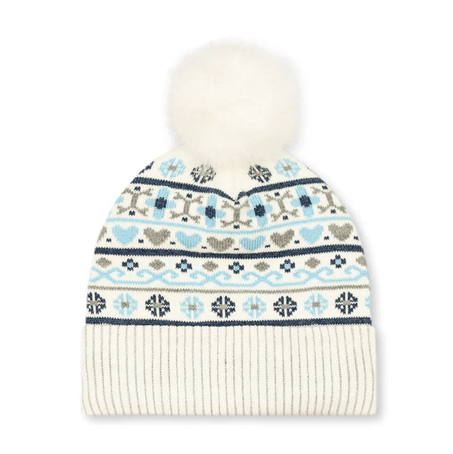 A cream-colored knit beanie hat featuring a white faux fur pom-pom on top and a colorful Fair Isle pattern with light blue, navy, and gray motifs on the upper section, finished with a solid cream ribbed cuff.
