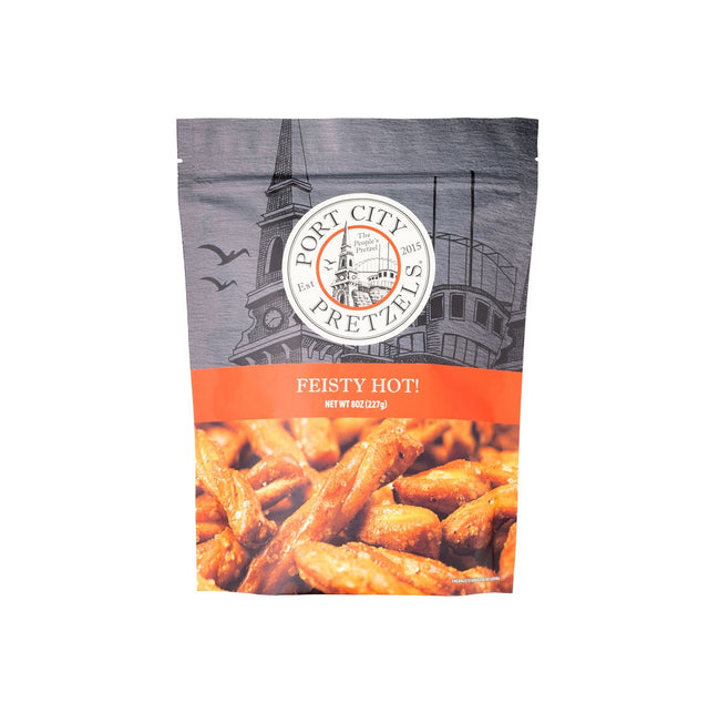 A bag of Port City Pretzels 'Feisty Hot!' snack pretzels, featuring a gray and white architectural background with an orange band and a photo of golden-brown pretzels at the bottom.