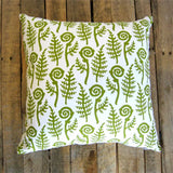 Decorative pillow with green fern pattern on a wooden background