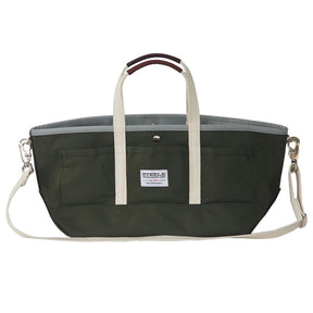 a wide olive green canvas tote with white straps and leather handles against a white background