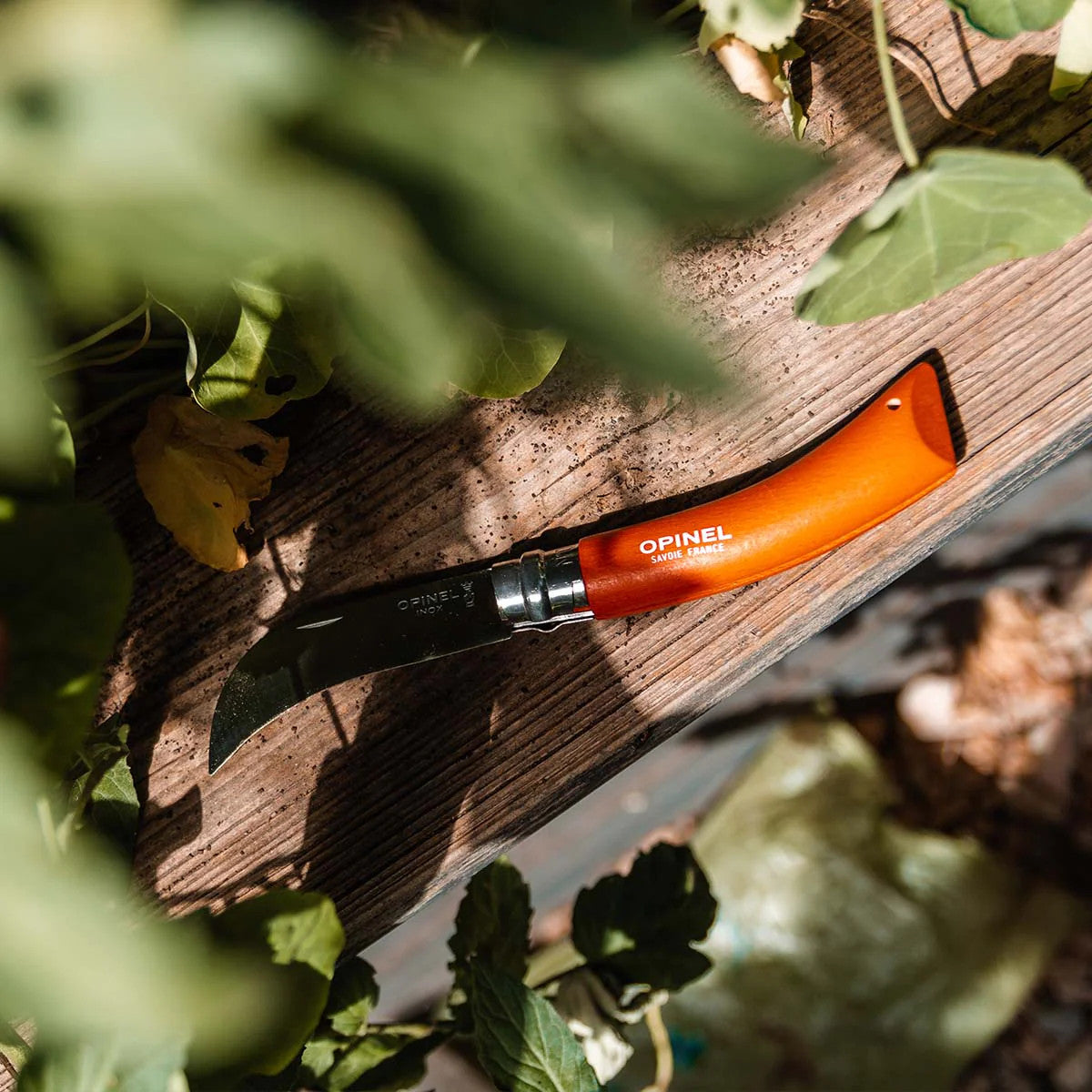 the No. 08 Pruning Knife with orange handle resting on a wooden garden bench