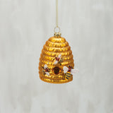 Decorative gold bee hive ornament with bees on a light gray background