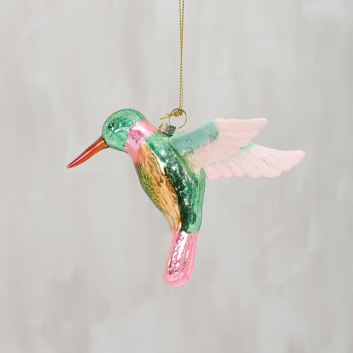 Colorful glass hummingbird ornament on a plain background