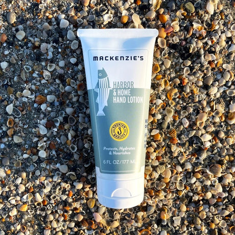 a bottle of the Harbor and Home Hand Lotion on a pebbled beach