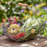 the large harvest basket on a garden table filled with corn, green beans, squash, and other freshly harvested veggies
