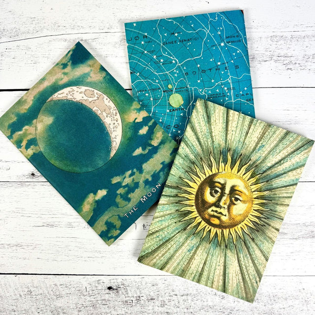 Three celestial-themed notebooks on a wooden surface