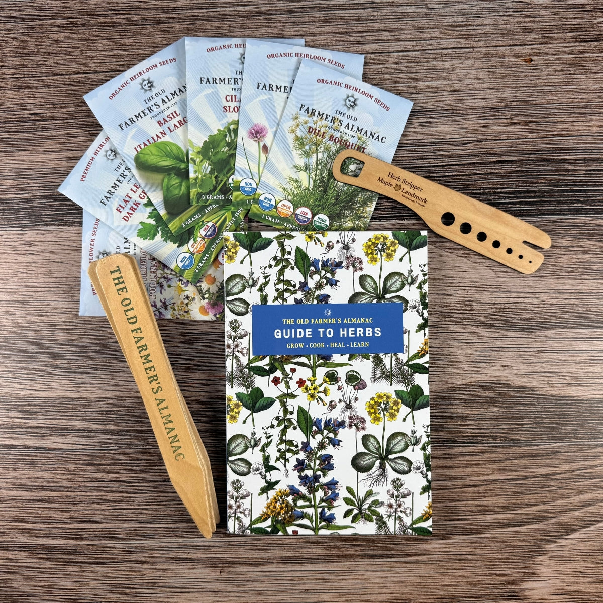 Set of 'The Old Farmer's Almanac' herb seed packets and a wooden tool on a wooden surface.