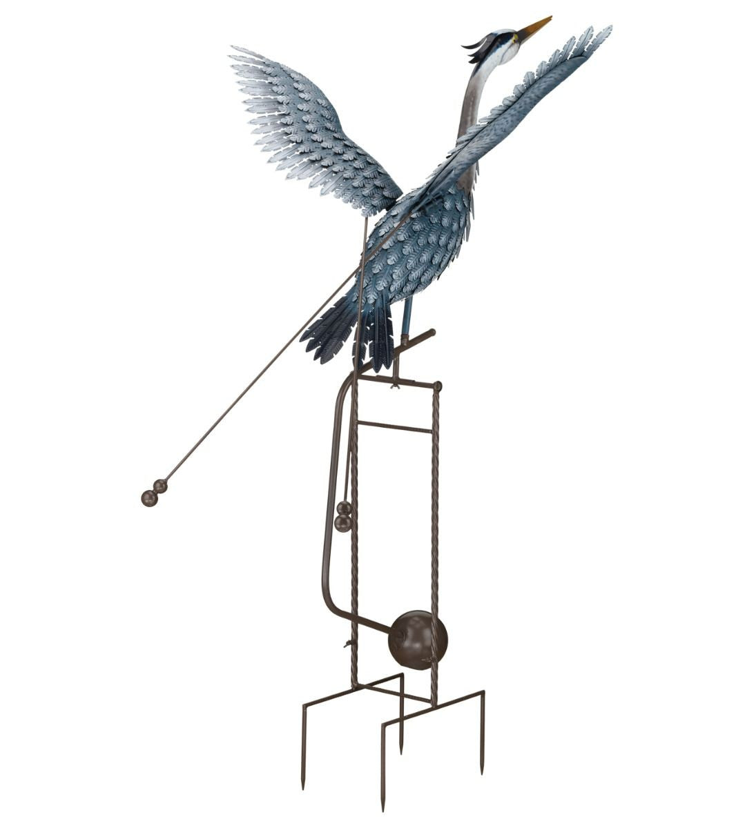 Full view of a metal heron sculpture in mid-flight, with outstretched wings and an elongated neck. The sculpture features detailed feather patterns and is mounted on a tall, sturdy frame with a spherical weight and pronged legs at the base. Two rods with weights are attached to the bird's body, enhancing its kinetic movement. The heron is painted in shades of blue and gray, and its long yellow beak is pointed forward.