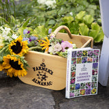 Wooden garden hod with flowers and a book titled 'Old Farmer's Almanac Flower Gardener's Handbook' on a garden background.