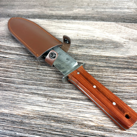 Knife with wooden handle and leather sheath on a wooden surface