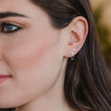 Close-up of a woman's ear wearing multiple earrings with a blurred background