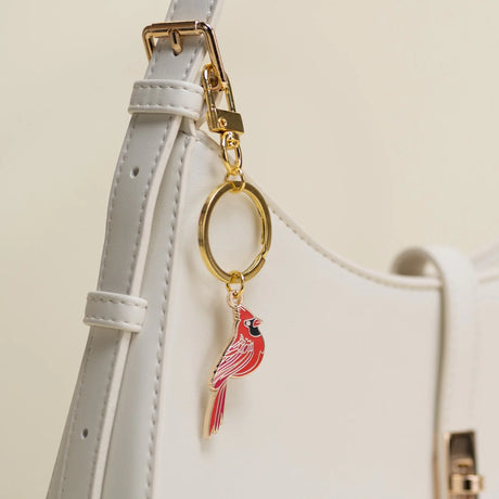 Keychain with a red cardinal charm attached to a white handbag.