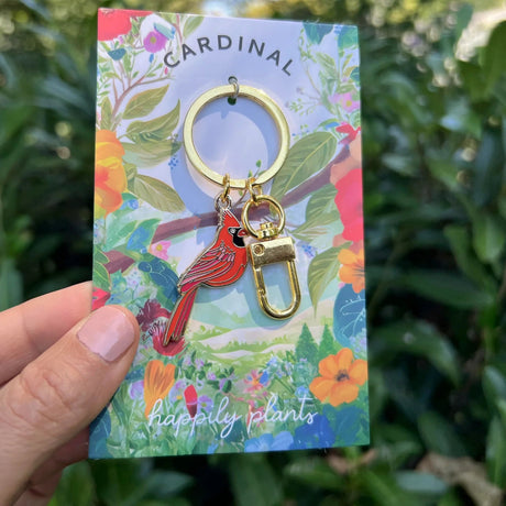 Cardinal keychain on a colorful 'happily plants' card with a green leafy background