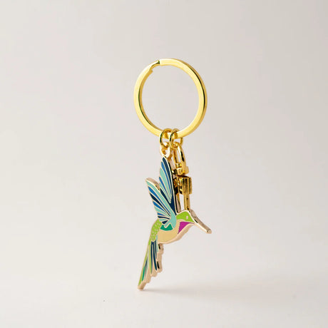 Gold keychain with a colorful hummingbird charm on a light gray background