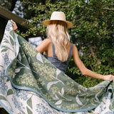 Woman holding a green floral-patterned towel outdoors