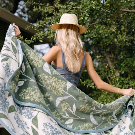 Woman holding a green floral-patterned towel outdoors
