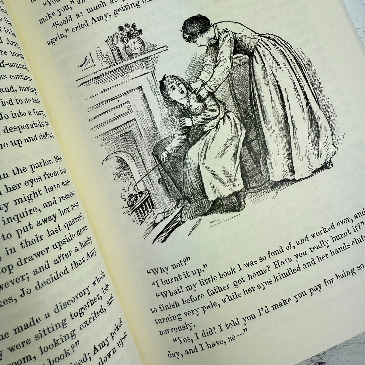 interior page of Little Women showing antique type face and vintage illustration of Amy burning Jo's book in the fireplace