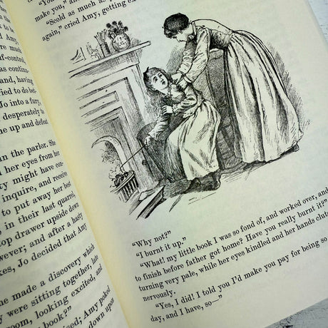 interior page of Little Women showing antique type face and vintage illustration of Amy burning Jo's book in the fireplace