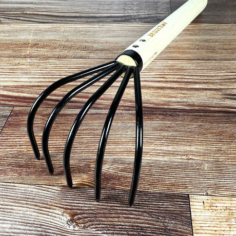 Close up of the black tines of the Long Handle Cultivator on a wooden surface