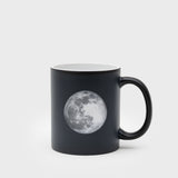 Black mug with a moon graphic on a light gray background